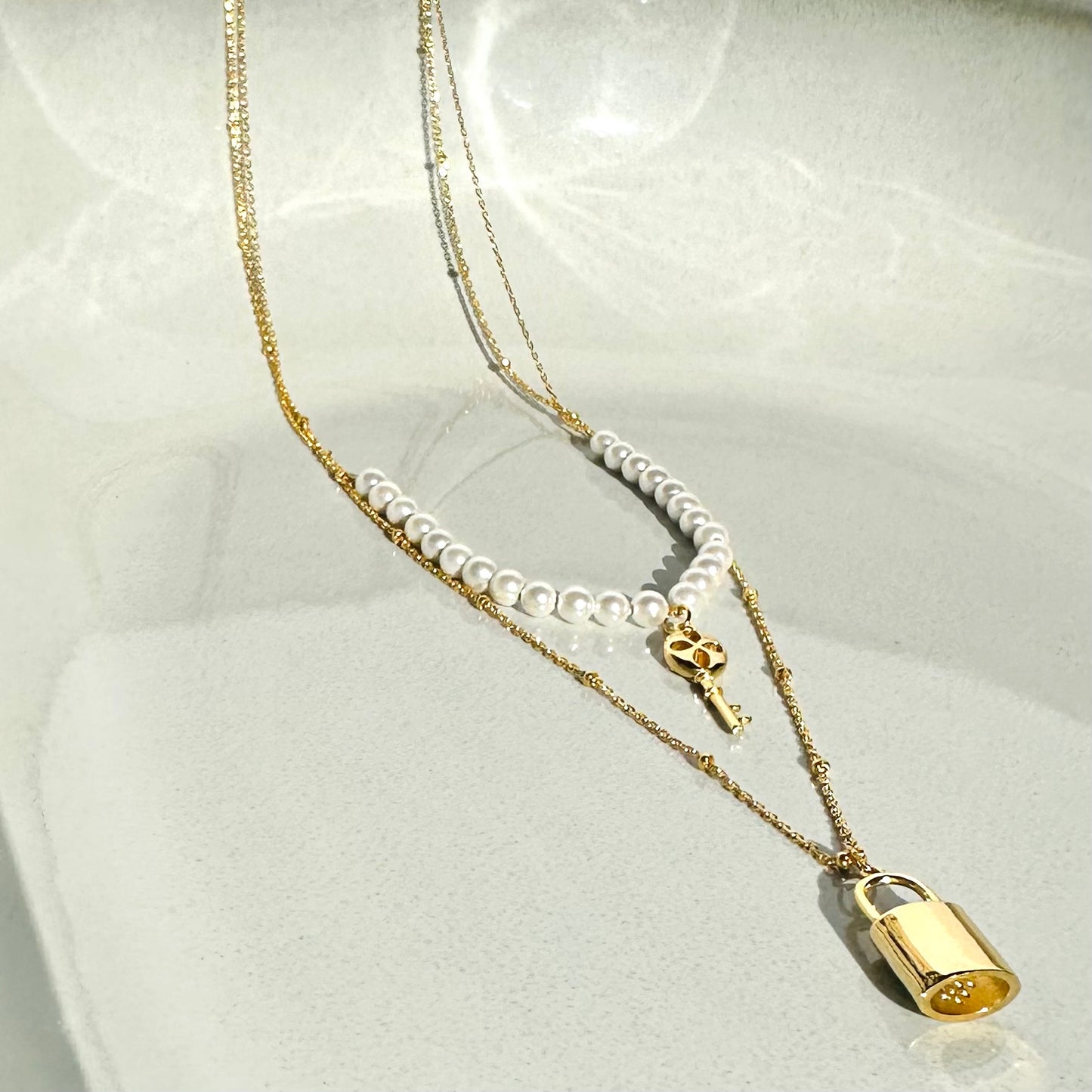 Collana multilivello in argento con perle di fiume lucchetto e chiave pendente